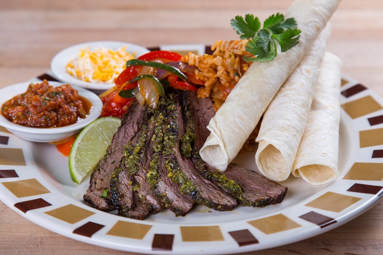 Sliced jalapeno steak fajitas with peppers, onions, flour tortillas, salsa and Spanish rice.