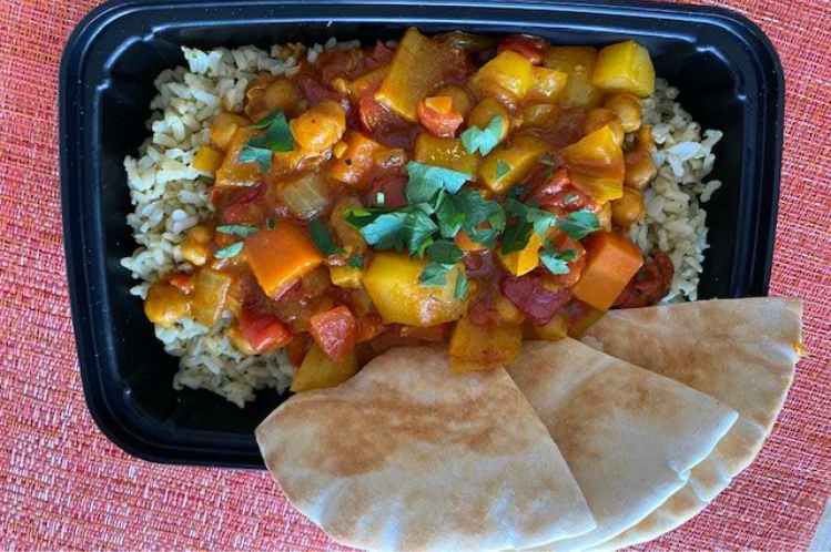 Moroccan vegetable and chickpea stew over brown rice with cilantro and lime, served with pita bread.