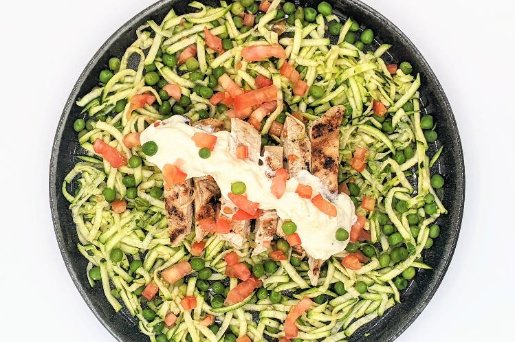 Low carb chicken Alfredo made with zucchini ribbons, diced tomato and peas.