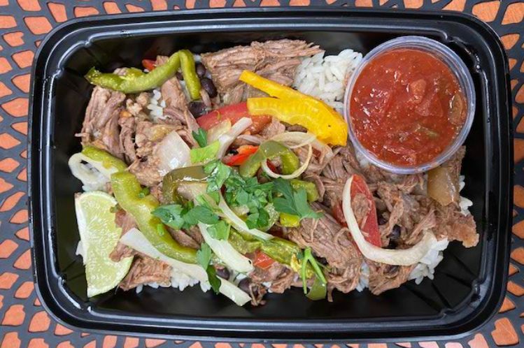 Shredded beef burrito bowl over rice with peppers, onions and a cup of salsa.