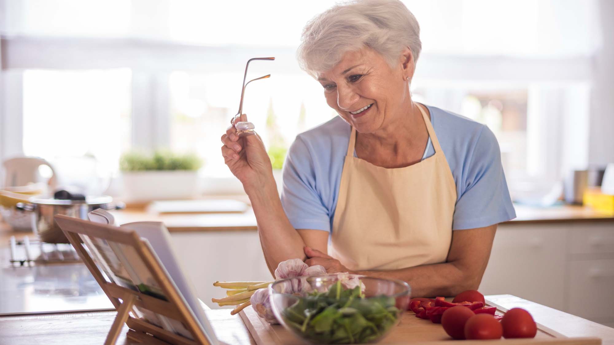 old-woman-looking-at-recipe-while-cooking-food